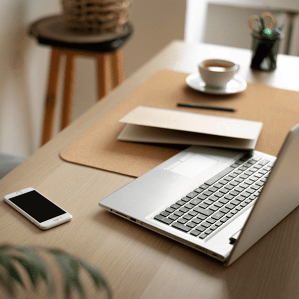 Mesa de escritório, com notebook, celular e café.